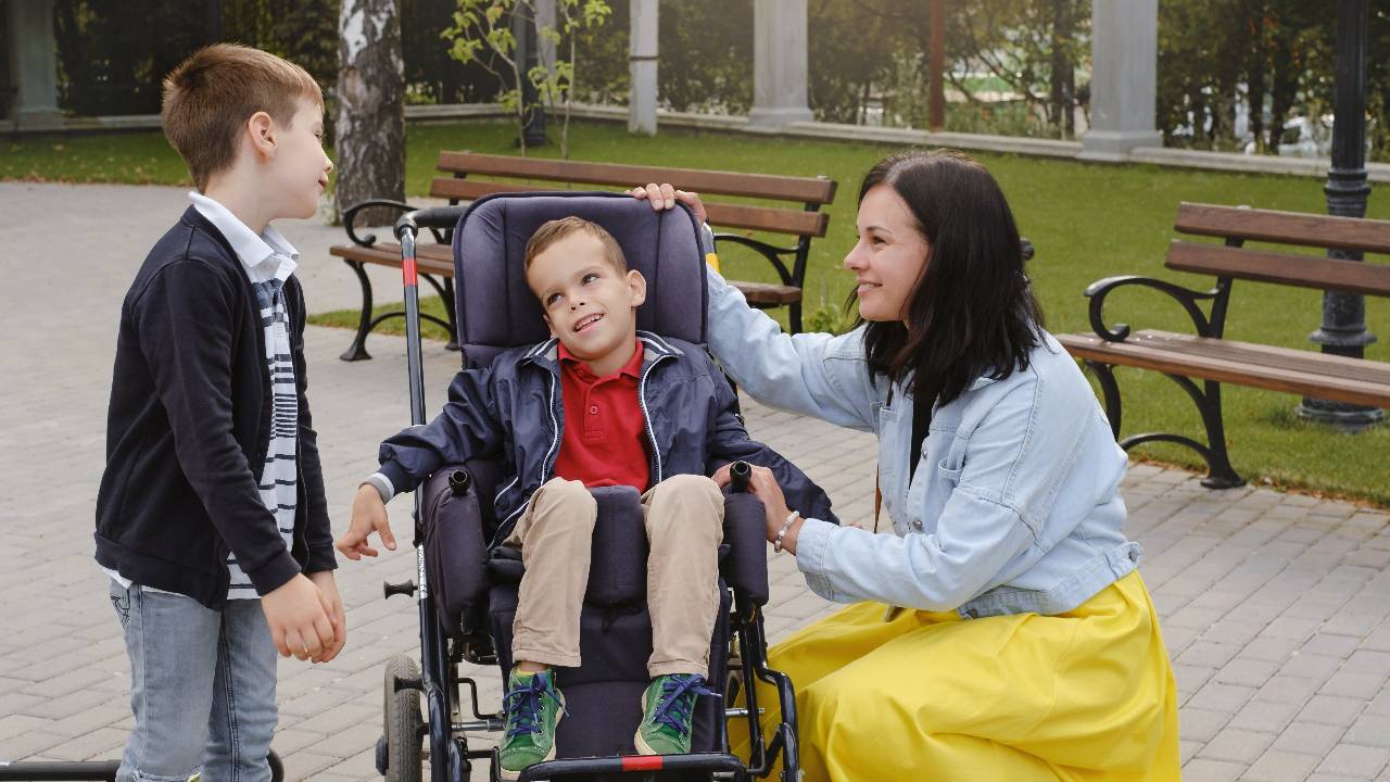 Family with cerebral palsy child on special wheelchair walking outdoors